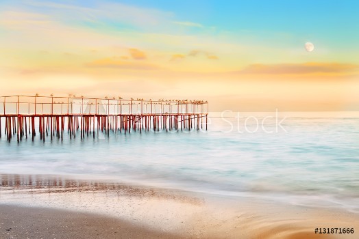 Picture of wonderful evening by the sea Long exposure blurred water waves dashing on the shore the old pier with seagulls soft focus